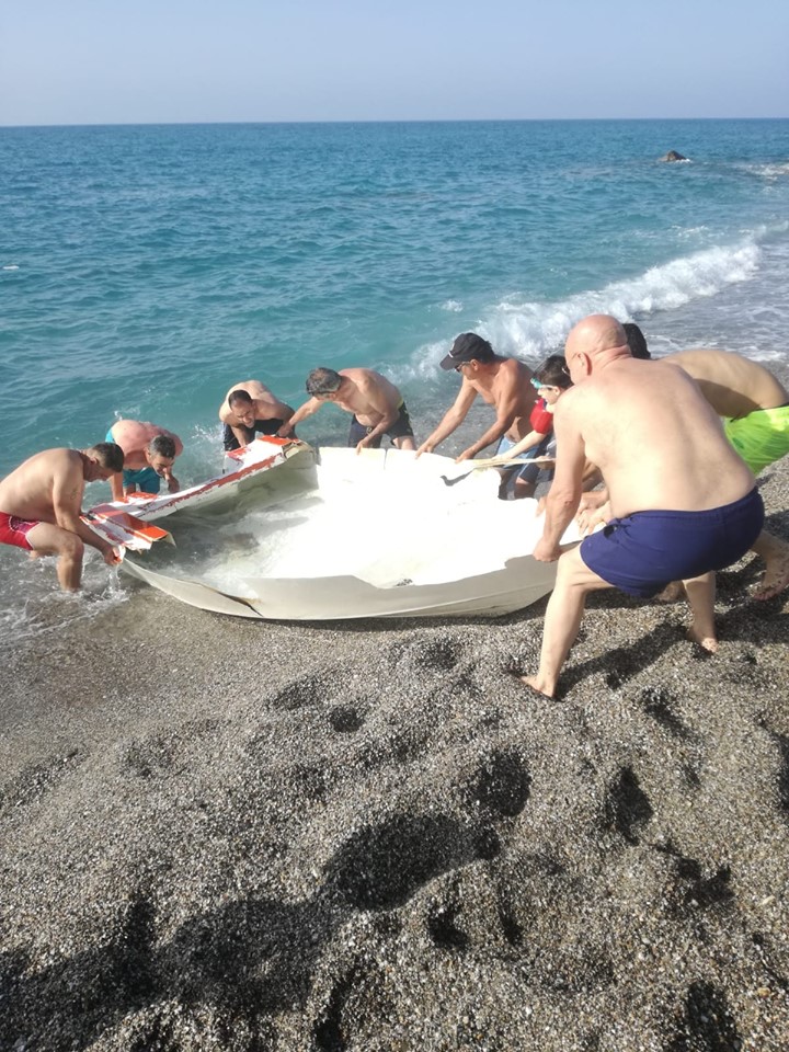 SPIAGGIA DELLE TARTARUGHE – A PonteNaso un gruppo di bagnanti tirano a secco il relitto di una barca